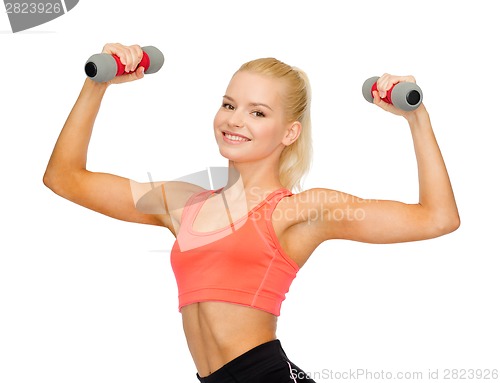 Image of smiling beautiful sporty woman with dumbbells