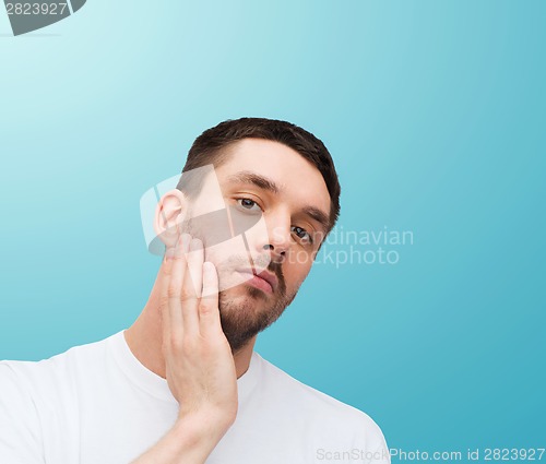 Image of beautiful calm man touching his face