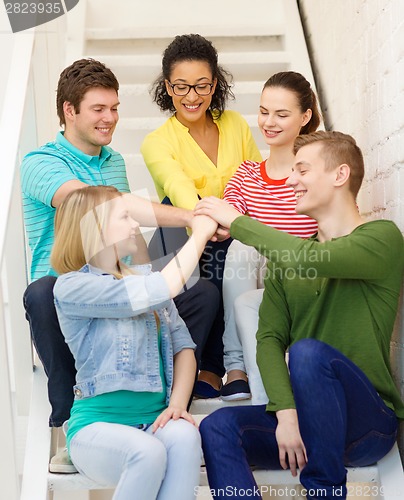 Image of smiling students with hands on top of each other