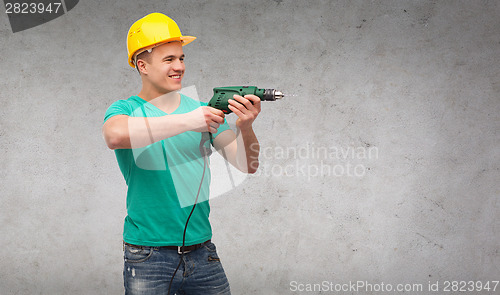 Image of smiling manual worker in helmet with drill machine