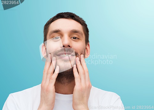 Image of beautiful smiling man touching his face