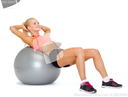 Image of smiling sporty woman exercising on fitness ball