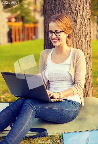 Image of smiling teenager in eyeglasses with laptop