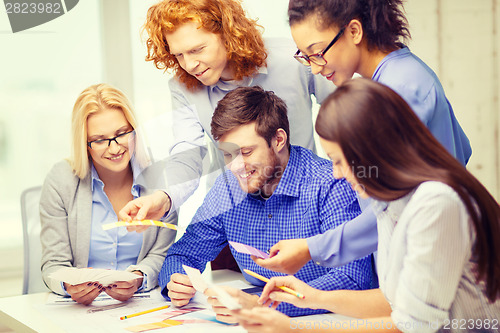 Image of smiling team with color samples at office