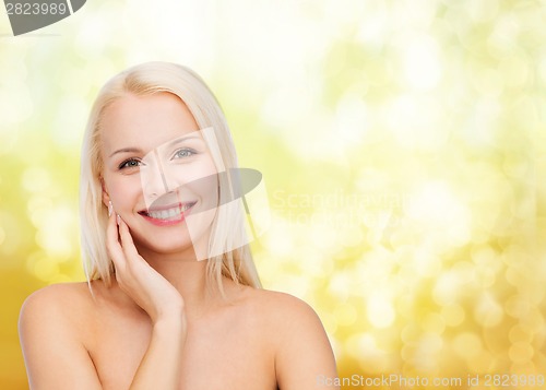 Image of smiling young woman touching her face skin