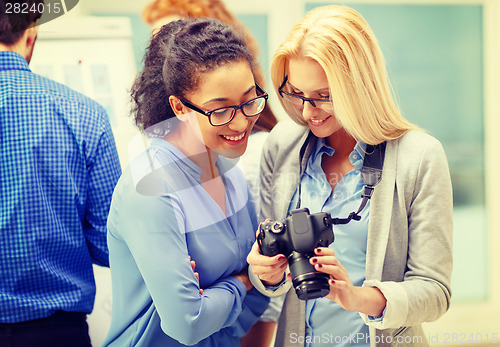 Image of two women looking at digital camera at office