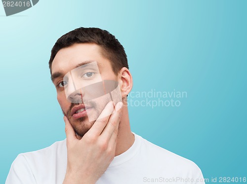 Image of beautiful calm man touching his face