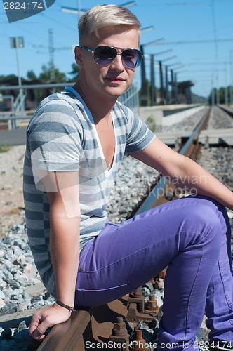 Image of Young man sitting on the rail track