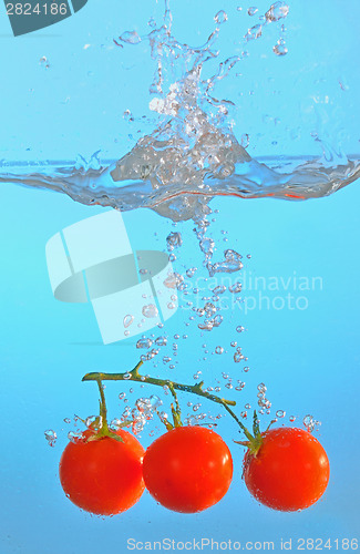 Image of red tomatoes thrown into clear water
