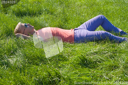 Image of Young trendy man lying on the grass
