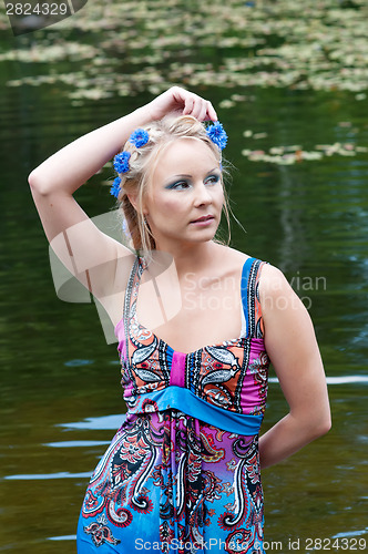 Image of Beautiful woman in dress standing near the pond