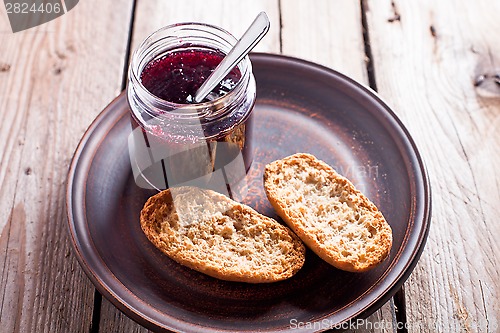 Image of black currant jam in glass jar and crackers