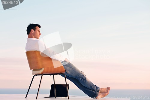 Image of relaxed young man at home on balcony