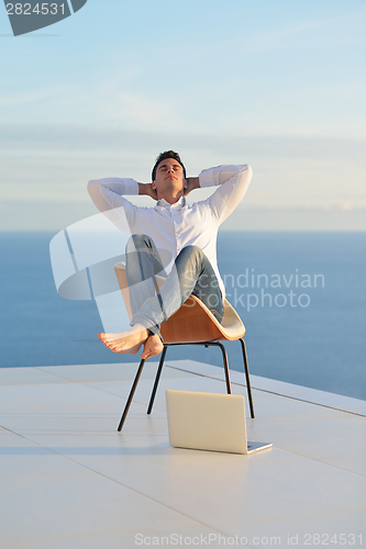 Image of relaxed young man at home on balcony