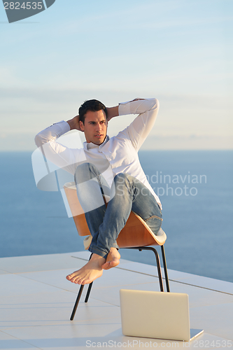 Image of relaxed young man at home on balcony