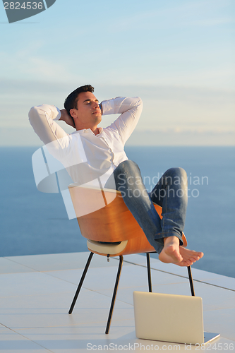 Image of relaxed young man at home on balcony