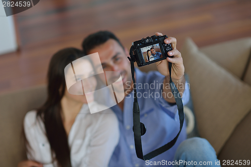 Image of couple playing with digital camera at home