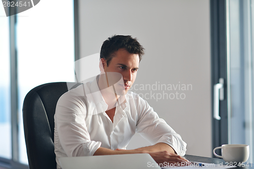 Image of frustrated young business man working on laptop computer at home