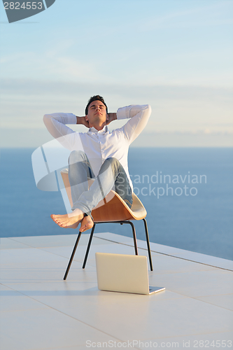 Image of relaxed young man at home on balcony