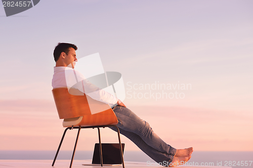 Image of relaxed young man at home on balcony