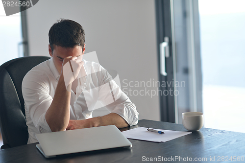 Image of frustrated young business man working on laptop computer at home