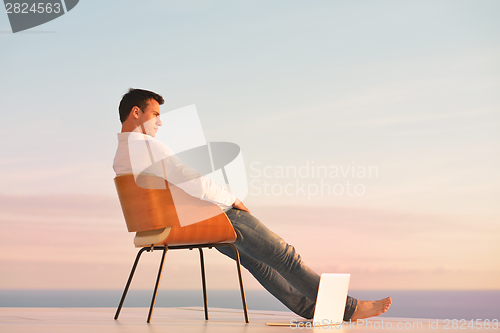 Image of relaxed young man at home on balcony