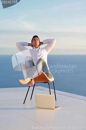 Image of relaxed young man at home on balcony