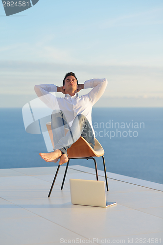 Image of relaxed young man at home on balcony