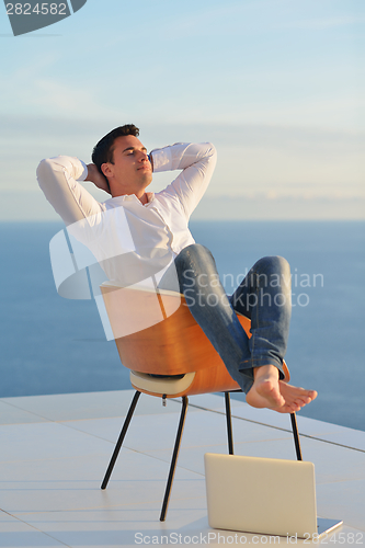 Image of relaxed young man at home on balcony