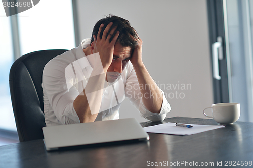 Image of frustrated young business man working on laptop computer at home