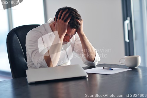 Image of frustrated young business man working on laptop computer at home
