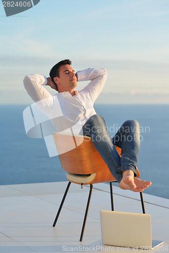 Image of relaxed young man at home on balcony