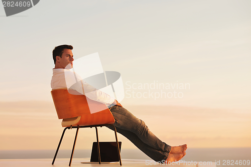 Image of relaxed young man at home on balcony