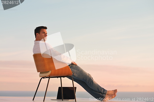 Image of relaxed young man at home on balcony