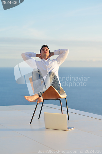 Image of relaxed young man at home on balcony