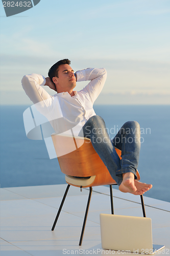 Image of relaxed young man at home on balcony