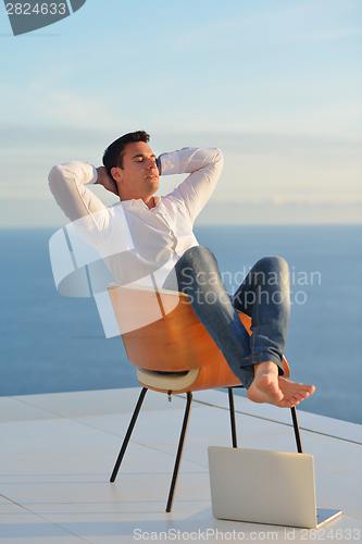 Image of relaxed young man at home on balcony