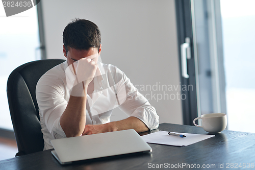 Image of frustrated young business man working on laptop computer at home