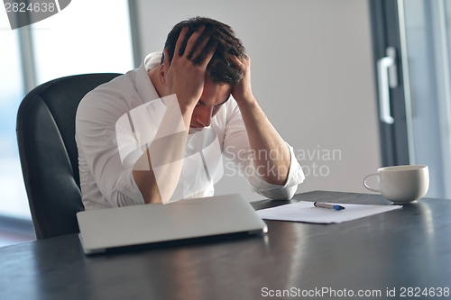 Image of frustrated young business man working on laptop computer at home
