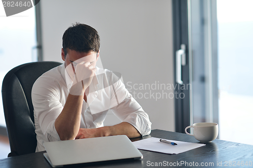 Image of frustrated young business man working on laptop computer at home