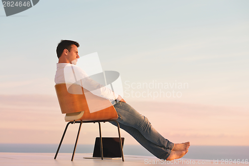 Image of relaxed young man at home on balcony