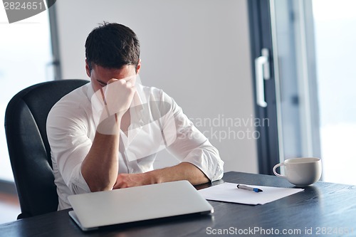 Image of frustrated young business man working on laptop computer at home