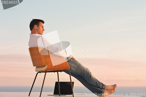 Image of relaxed young man at home on balcony