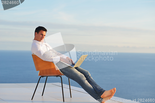 Image of relaxed young man at home on balcony