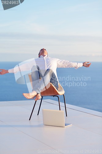 Image of relaxed young man at home on balcony