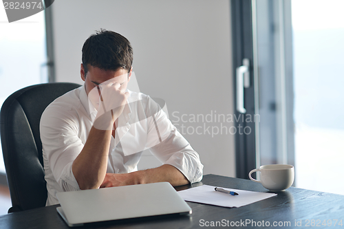 Image of frustrated young business man working on laptop computer at home