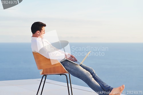 Image of relaxed young man at home on balcony