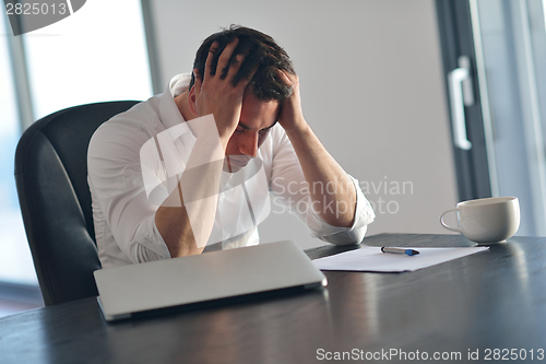 Image of frustrated young business man working on laptop computer at home