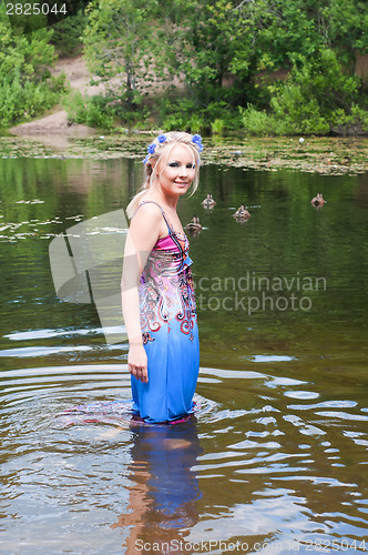 Image of Beautiful woman in dress standing in pond