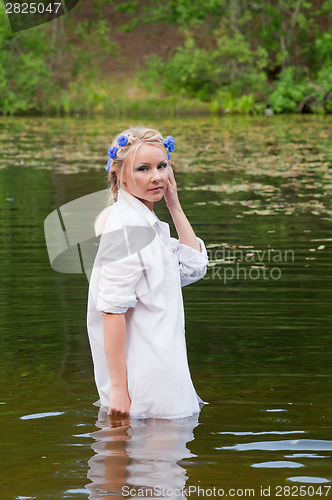 Image of Beautiful woman in white standing in pond